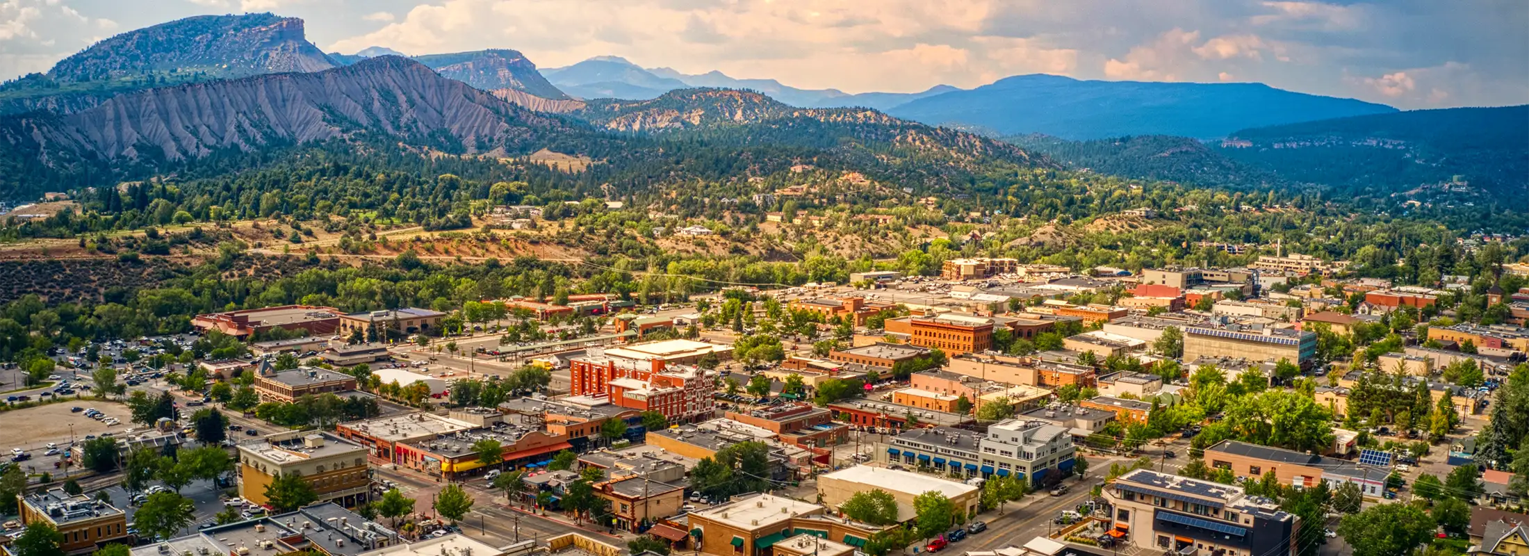 Aerial view of Durango, Colorado, showcasing the city against a backdrop of mountains and green landscape.