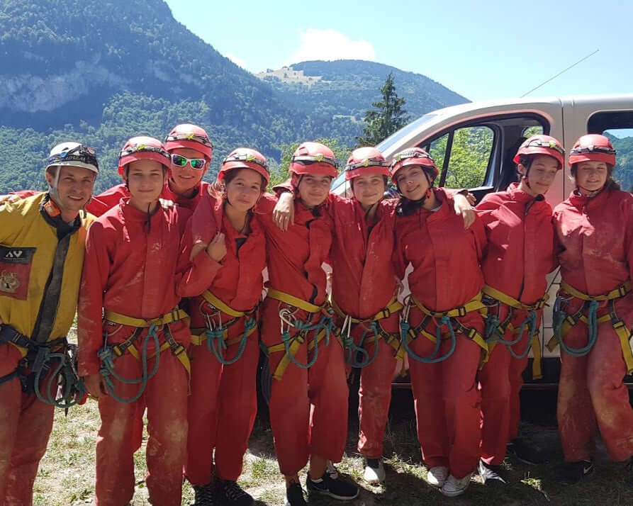 Group of teens in climbing gear ready for adventure at a summer camp in the Alps, showcasing teamwork and excitement.