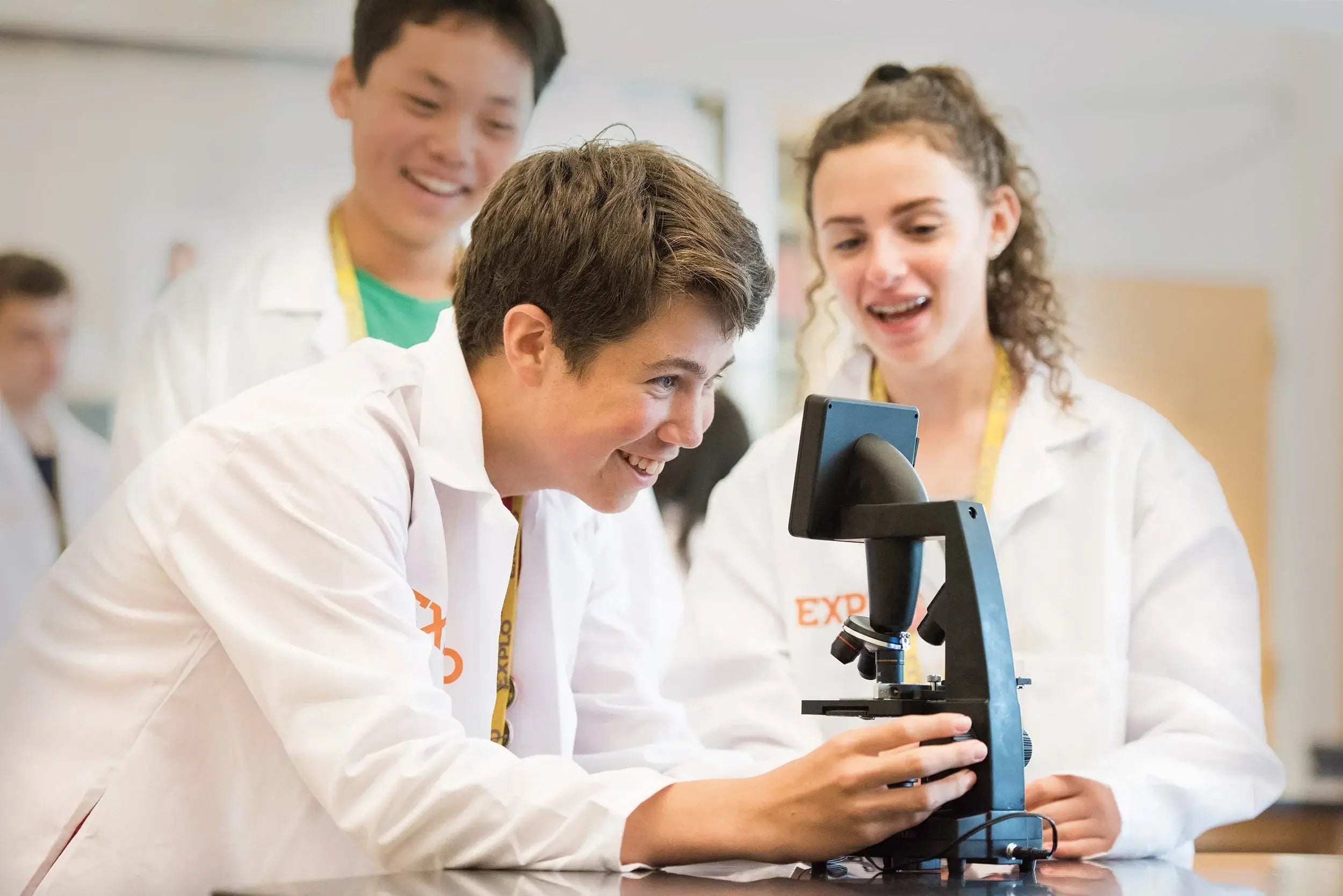 Middle school students engaged in a summer program science workshop, exploring with a microscope at EXPLO.