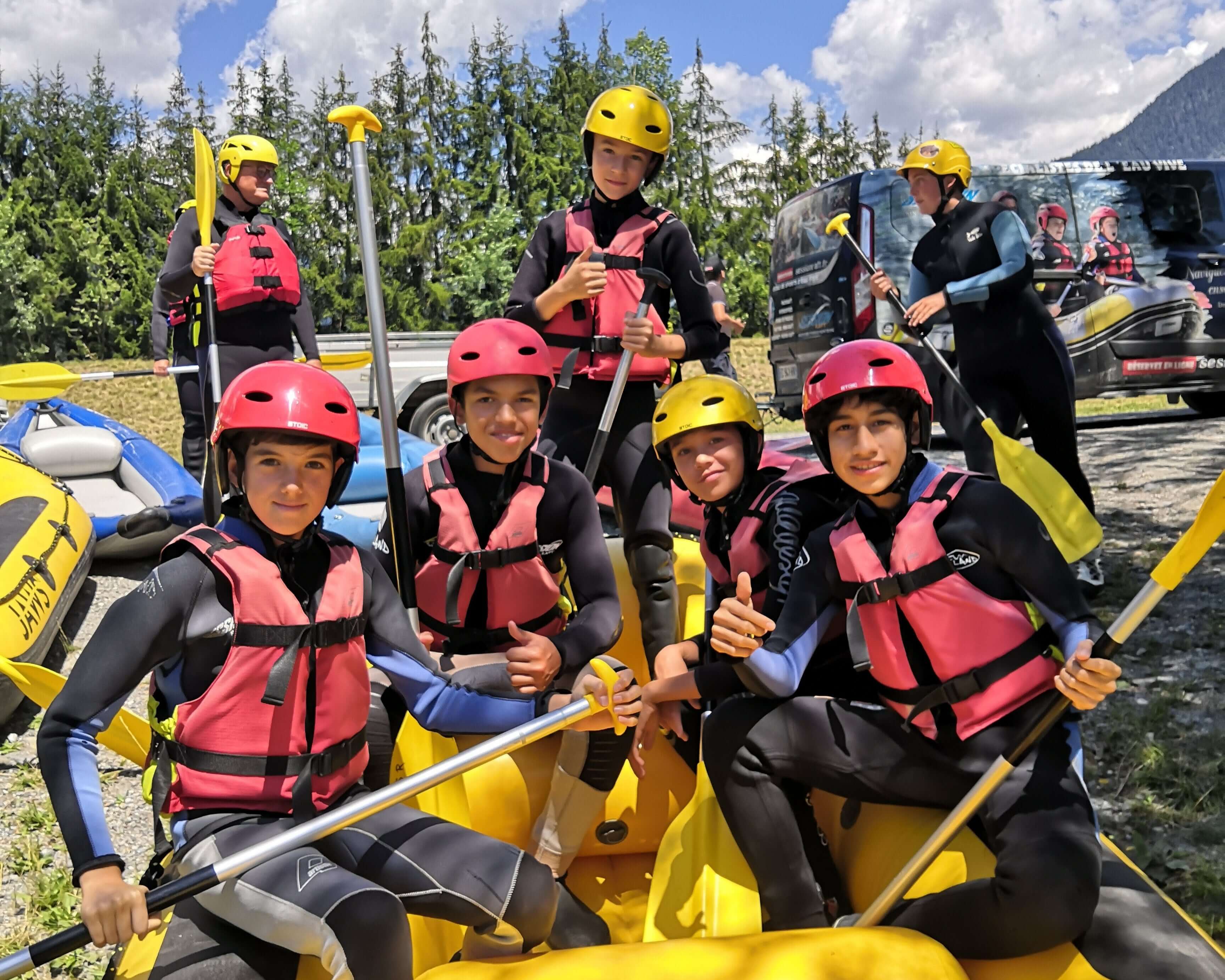 Teens in pink life vests enjoying rafting at a summer camp in the French Alps, ready for adventure and new friendships.