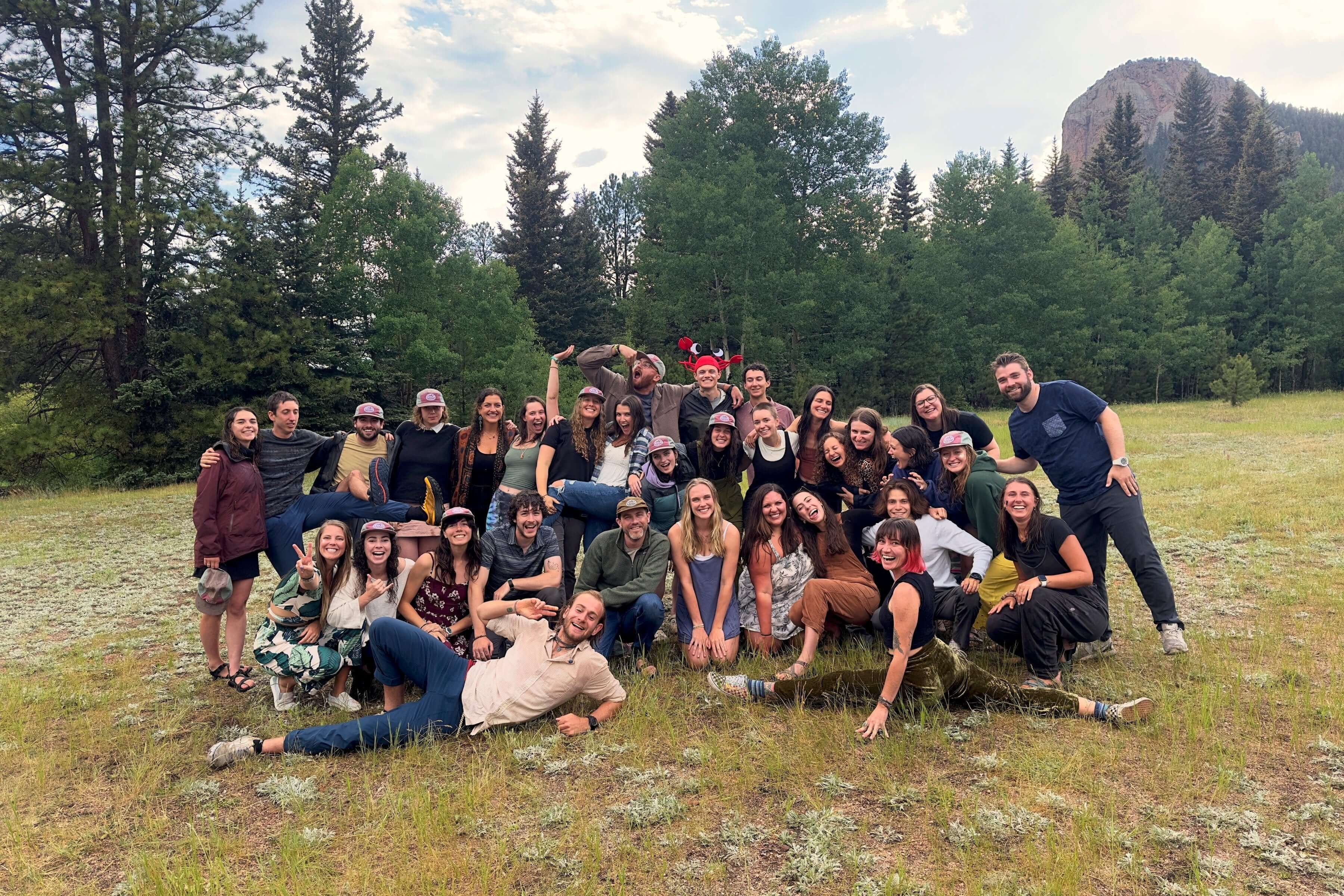 Group of summer trip leaders posing together in a lush outdoor setting, showcasing teamwork and adventure spirit.