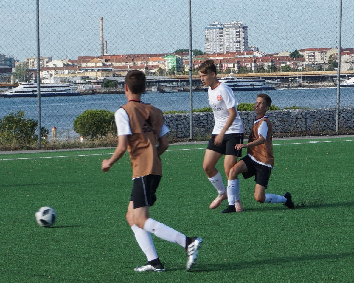 Young soccer players training on a field during a summer camp near water.