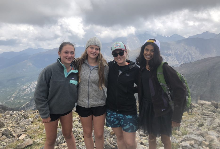 Four teens enjoying summer adventure at a mountain peak in Colorado, perfect for summer camps and travel experiences.