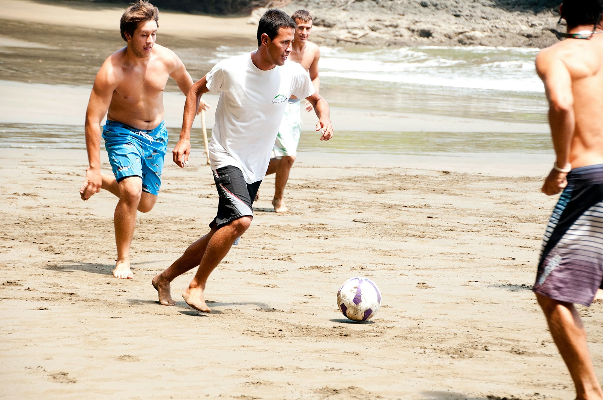 Teens playing soccer on a beach in Costa Rica, enjoying summer programs and travel experiences.