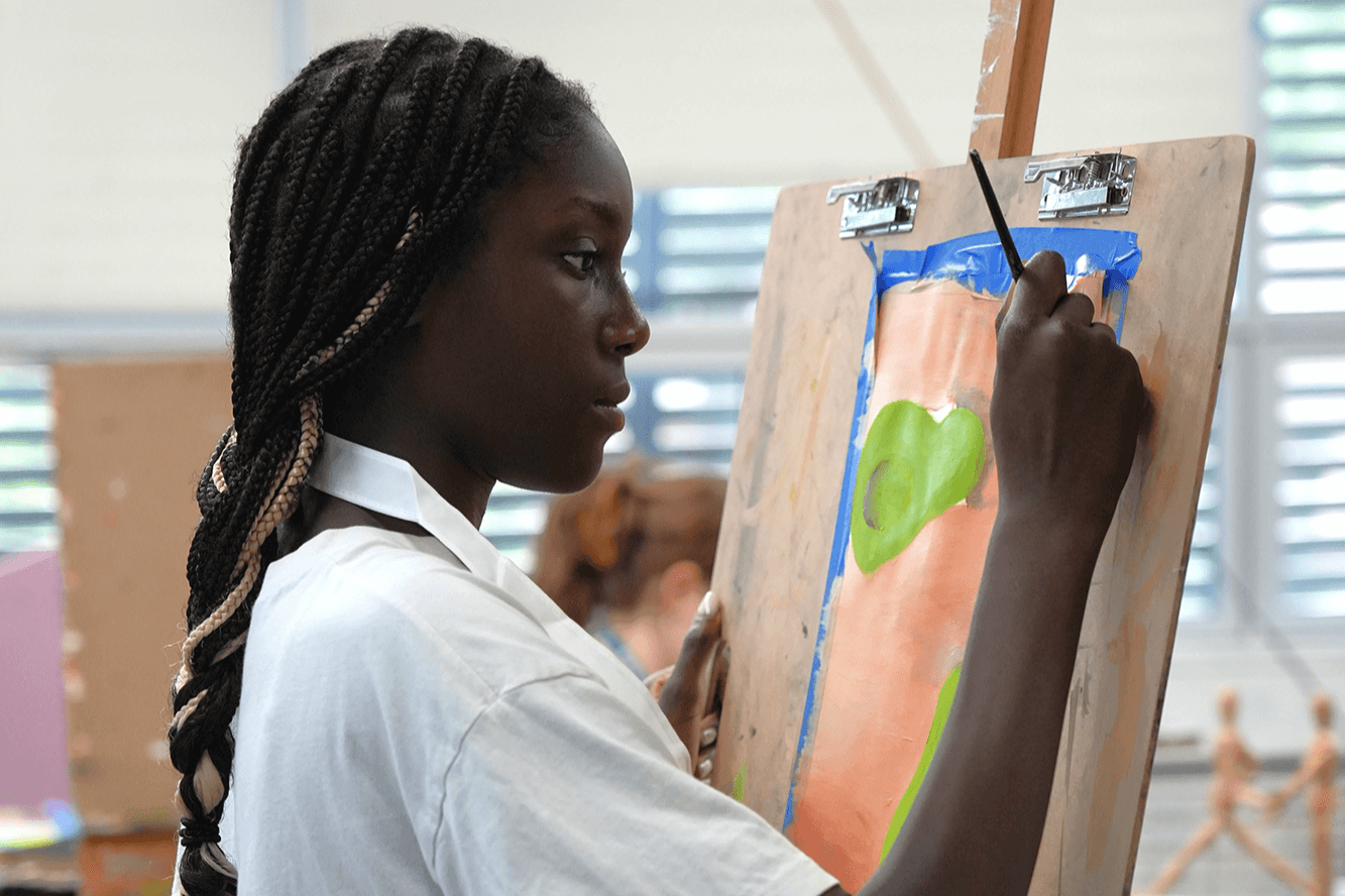 middle school student painting on an easel during a creative workshop at a summer program