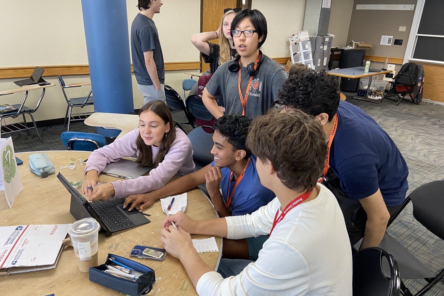 High school students collaborating on a laptop during a summer program, actively engaging in project work.