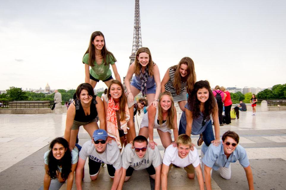 Teen travelers joyfully posing in front of the Eiffel Tower while participating in a summer program.