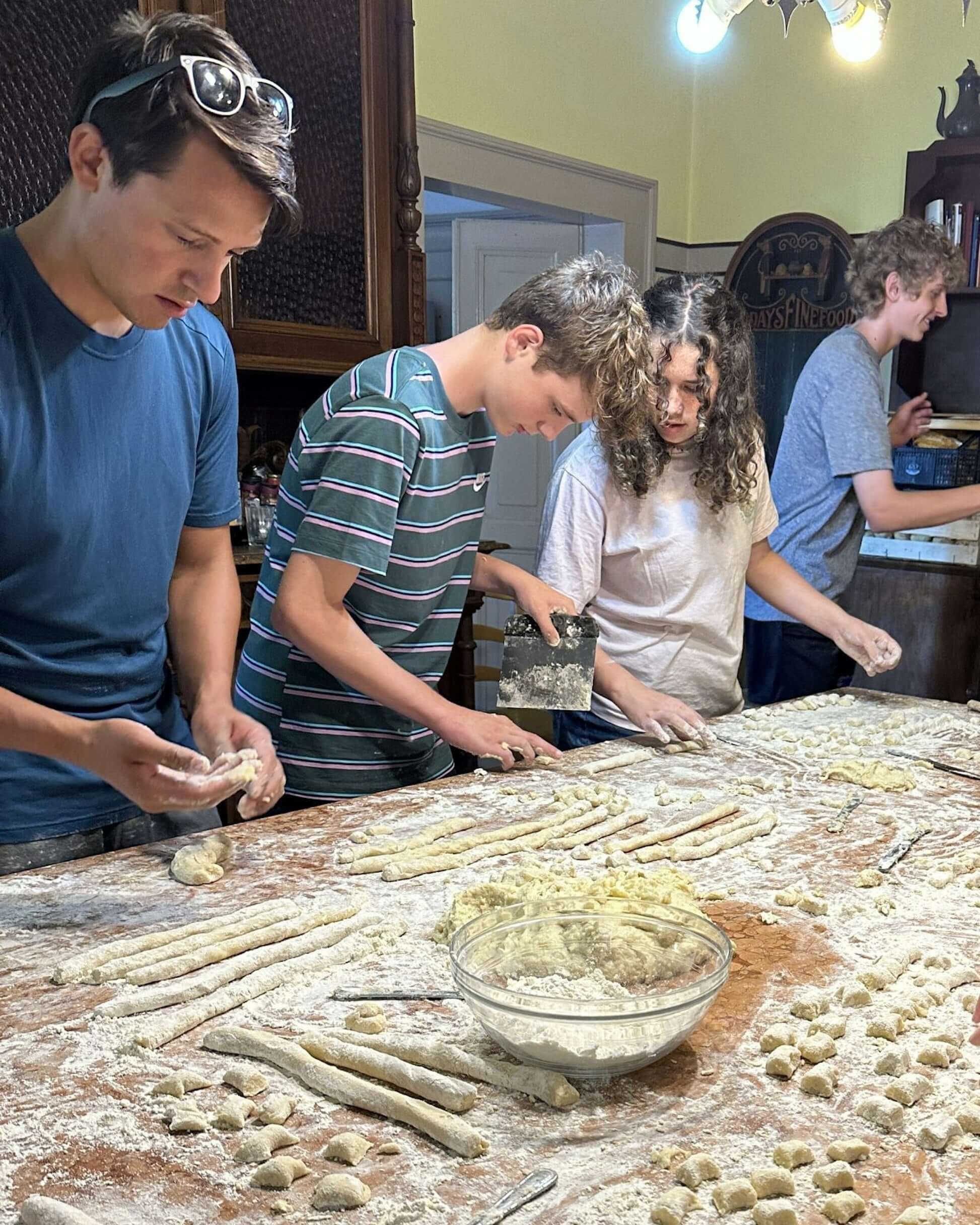 Students making pasta together in a rustic Italian kitchen during their Northern Italy adventure.