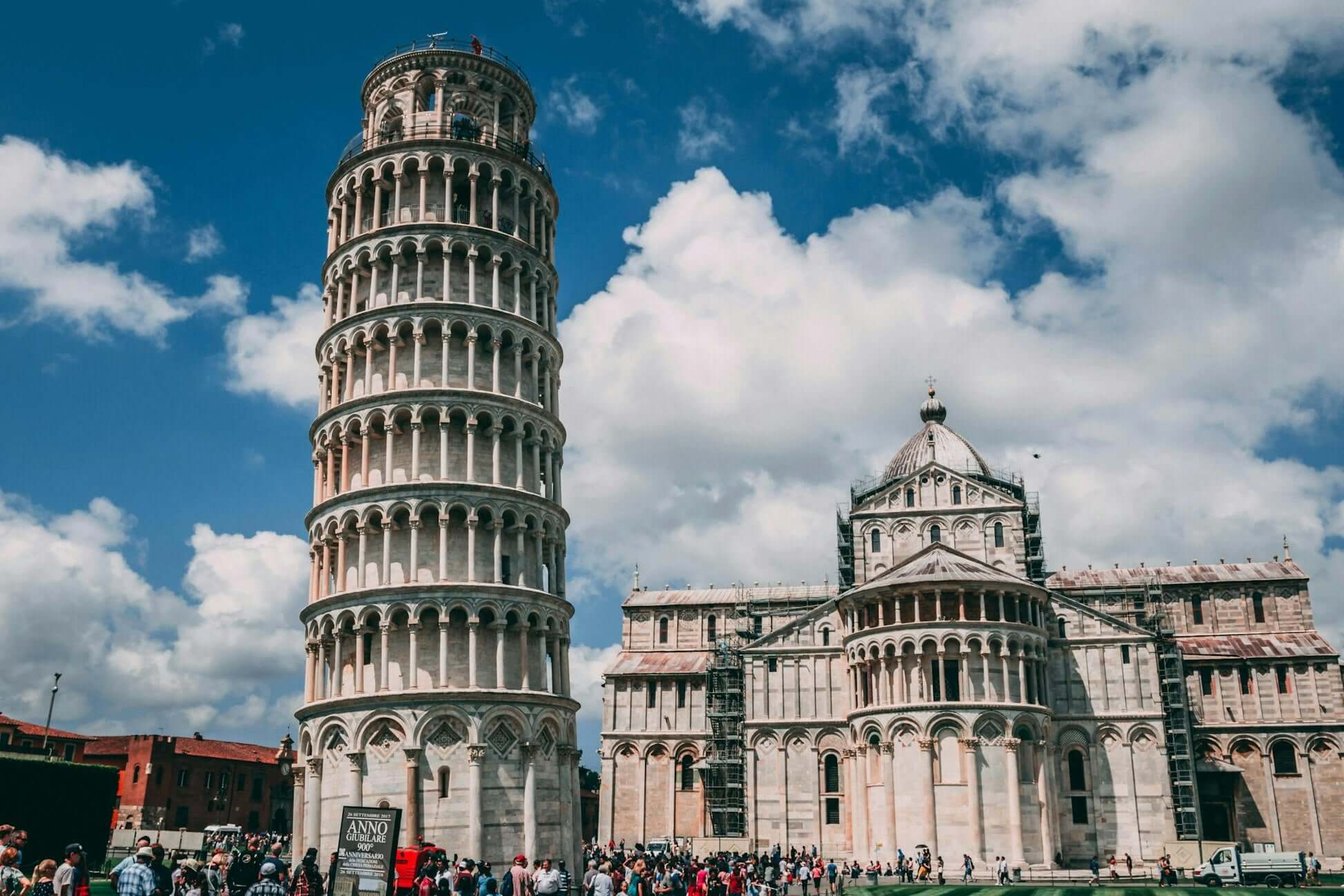 Leaning Tower of Pisa surrounded by tourists, showcasing its iconic architecture against a blue sky.