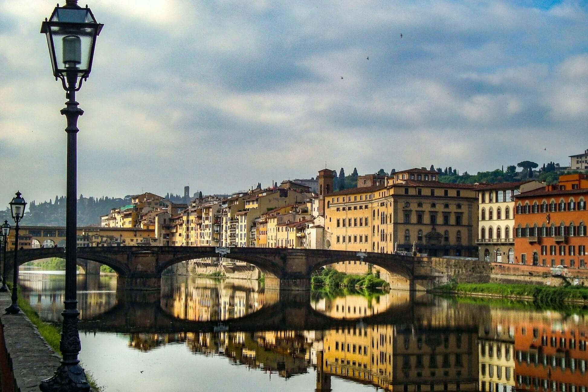 Scenic view of Florence's Arno River with historic buildings reflecting in the water, perfect for high school summer programs.