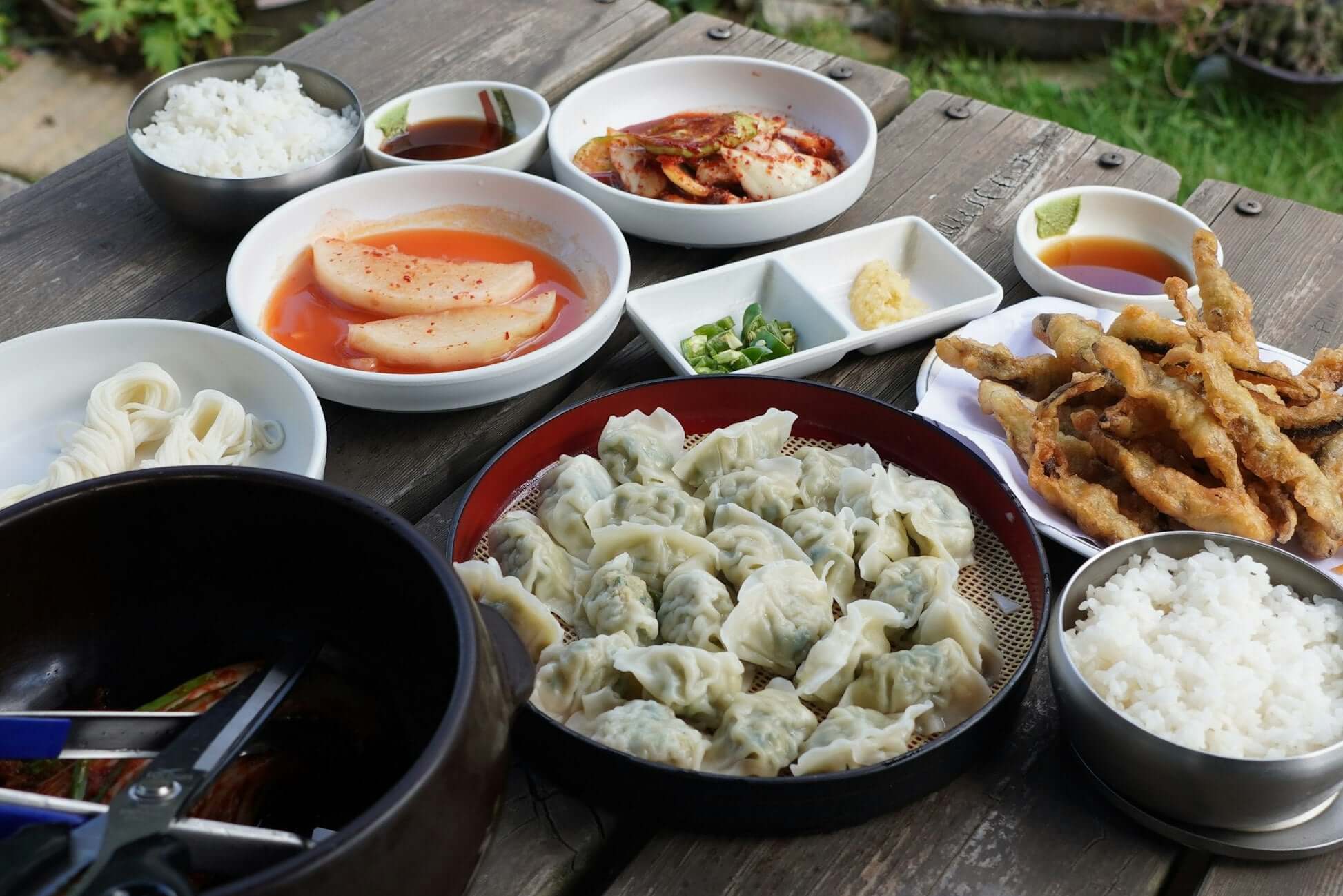 Traditional South Korean meal featuring dumplings, rice, and assorted side dishes on a wooden table.