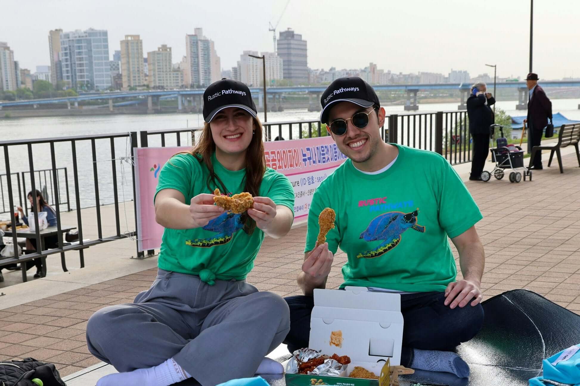 Teen travelers enjoying Korean street food with Rustic Pathways by the river in South Korea.