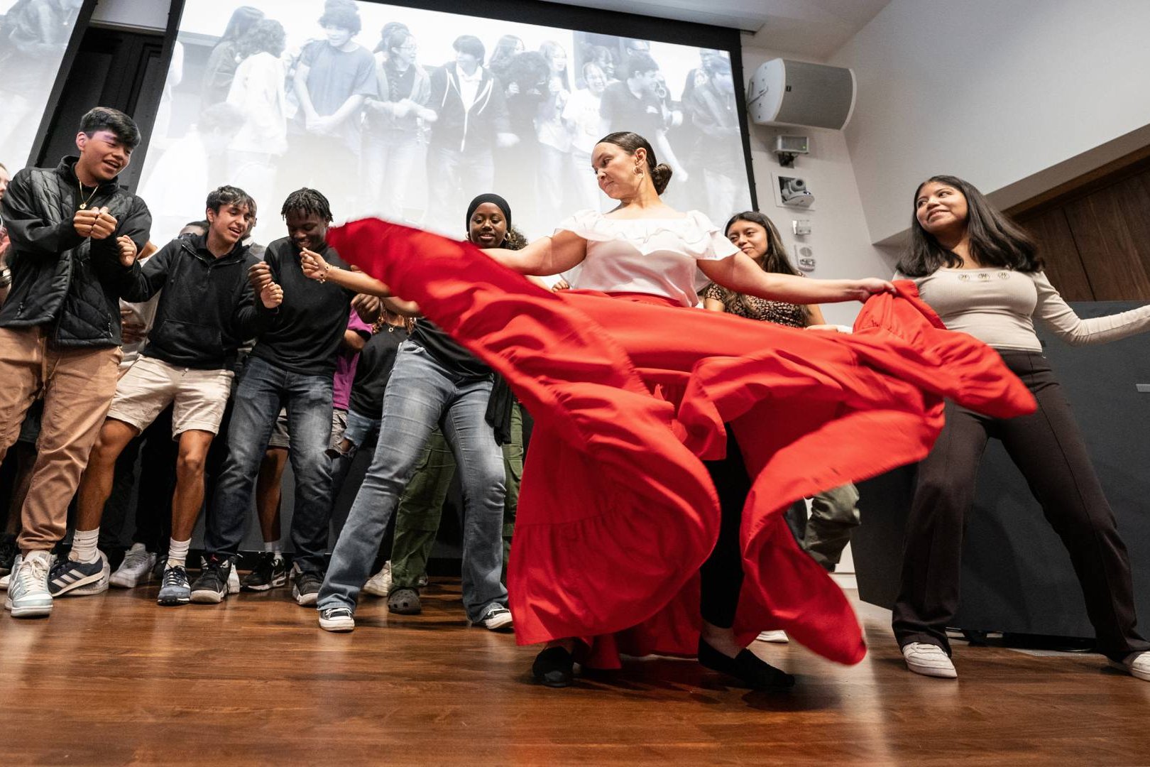 Students enjoying a lively dance performance, showcasing vibrant red fabric in a dynamic cultural celebration.