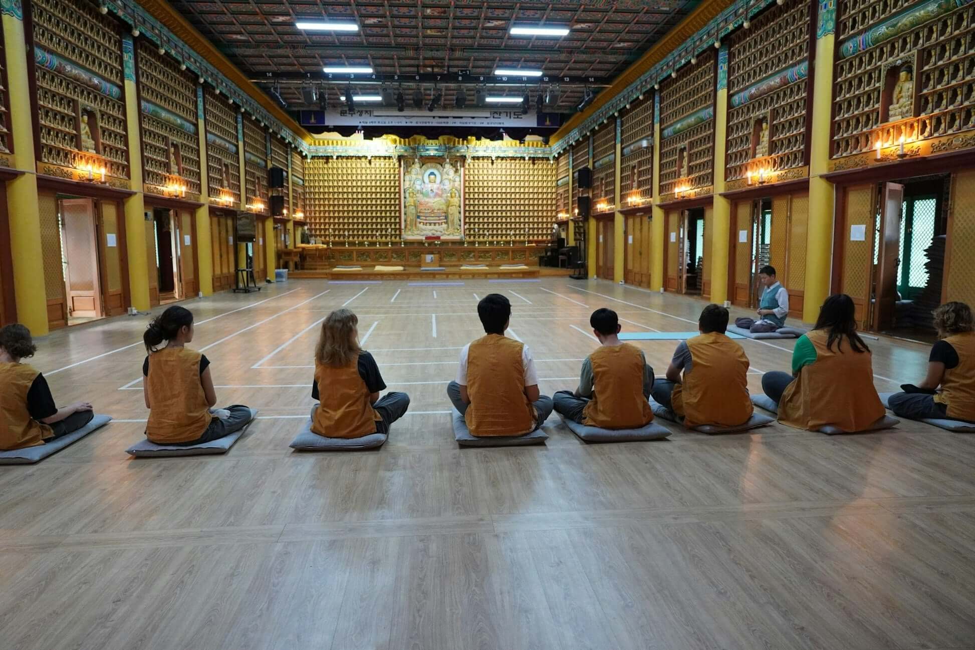 Teens participating in a meditation session in a tranquil South Korean temple setting.