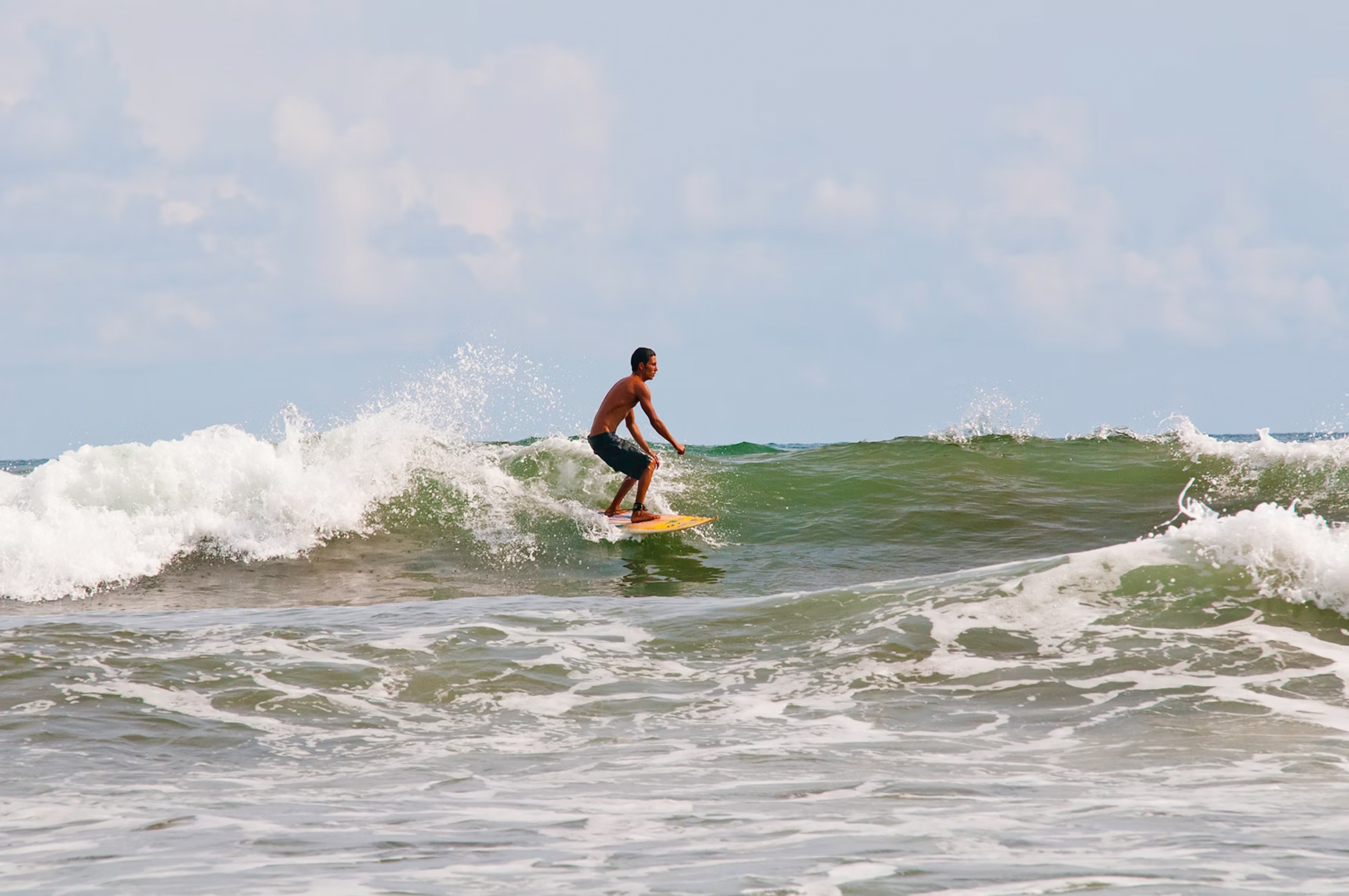 Teen surfing on a vibrant wave, capturing the thrill of summer camps and teen travel adventures.