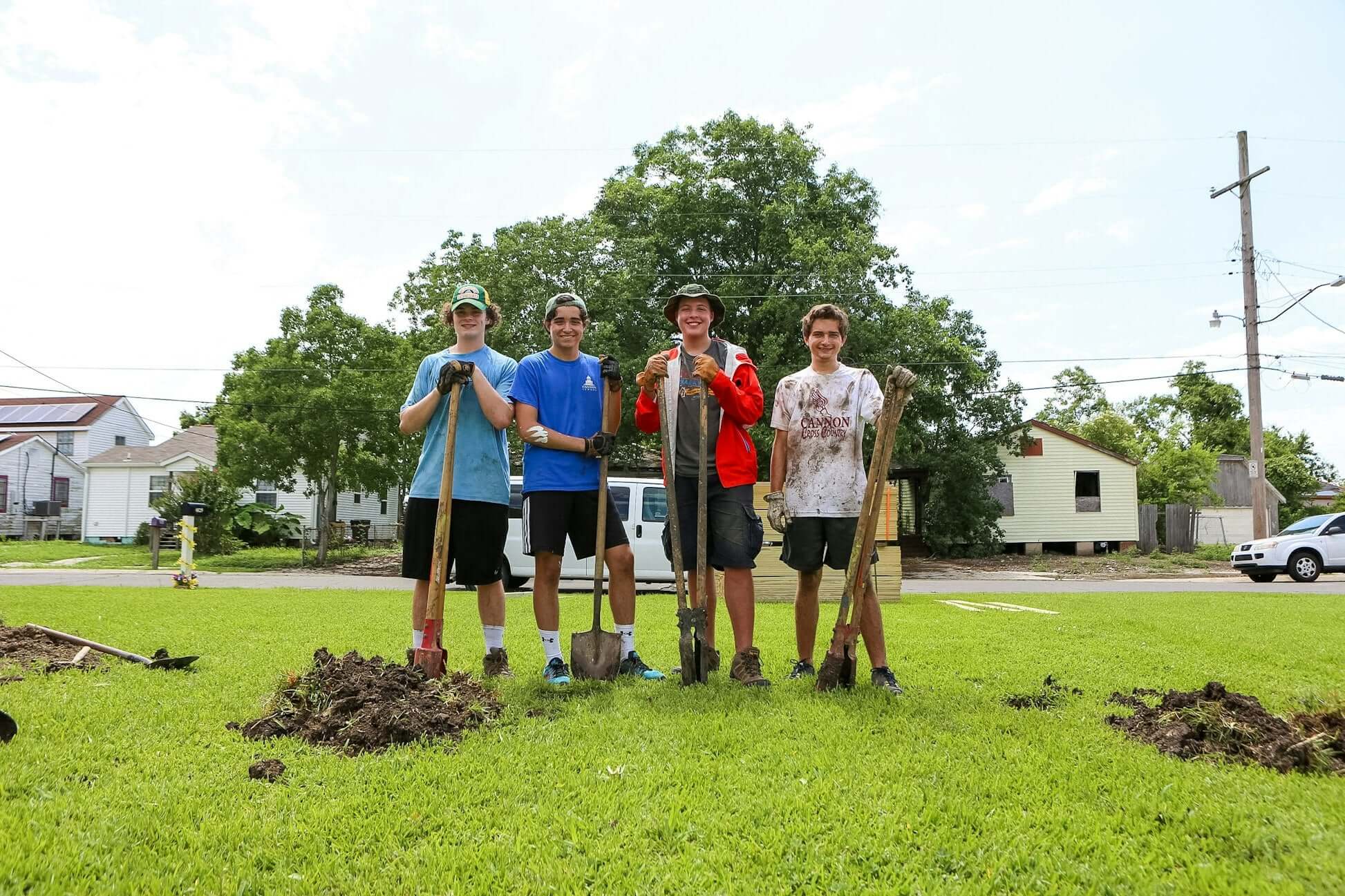 High school students volunteering in New Orleans, participating in community rebuilding efforts with shovels.