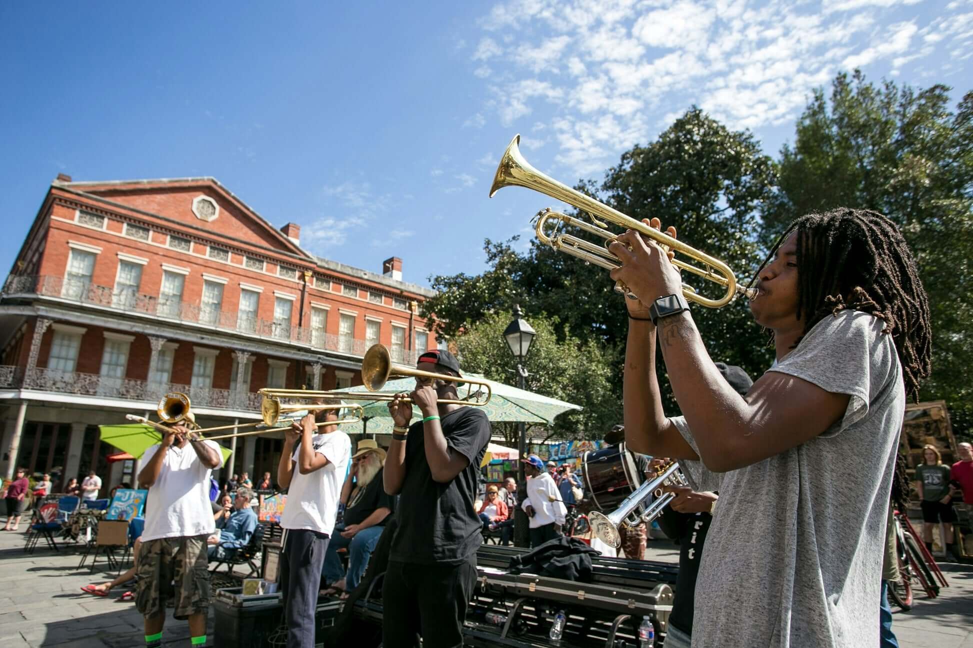 Musicians performing with trumpets in New Orleans' vibrant French Quarter, showcasing local culture and community spirit.