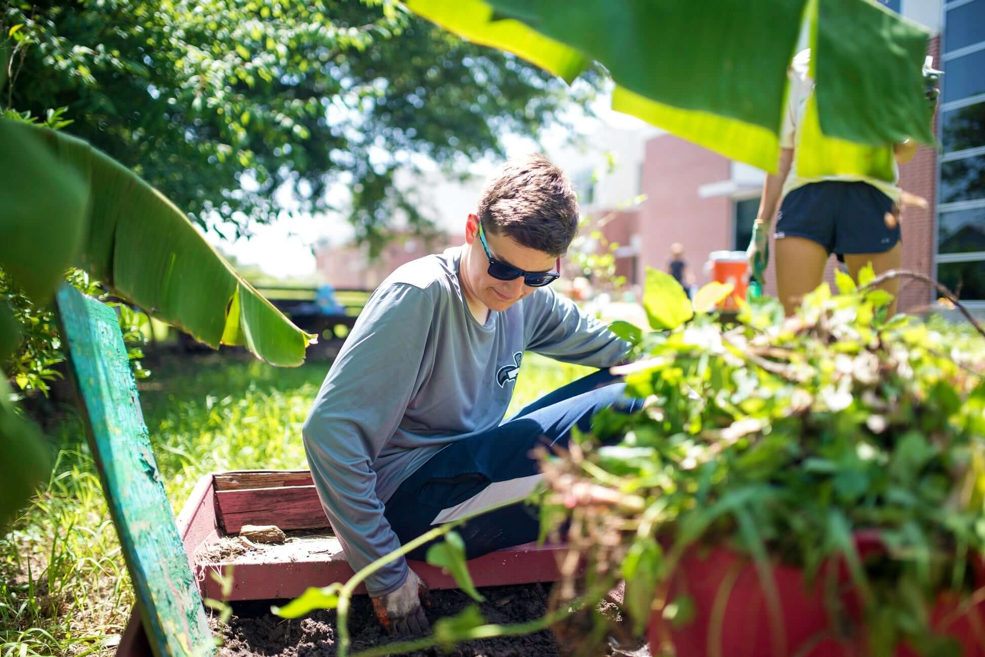 High school student participating in community gardening project in New Orleans, rebuilding after climate challenges.