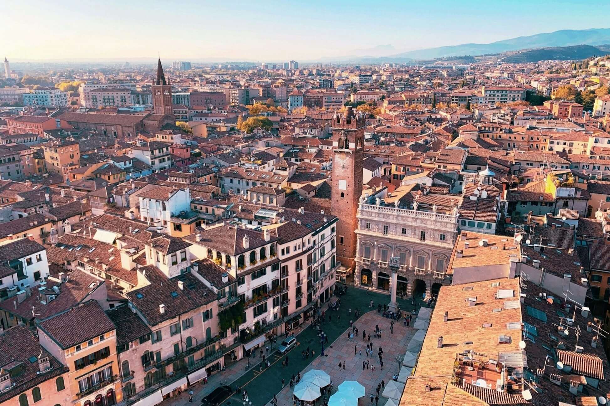 Aerial view of a charming Italian city with terracotta roofs, showcasing historic buildings under a clear sky. Perfect for student travel.