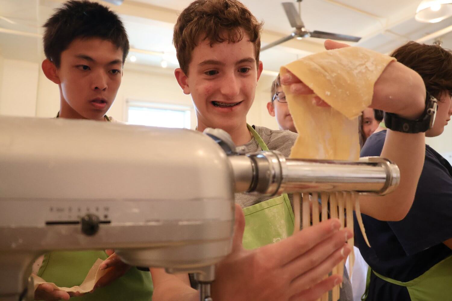 middle school students enjoying a summer camp cooking class, making fresh pasta together at EXPLO program