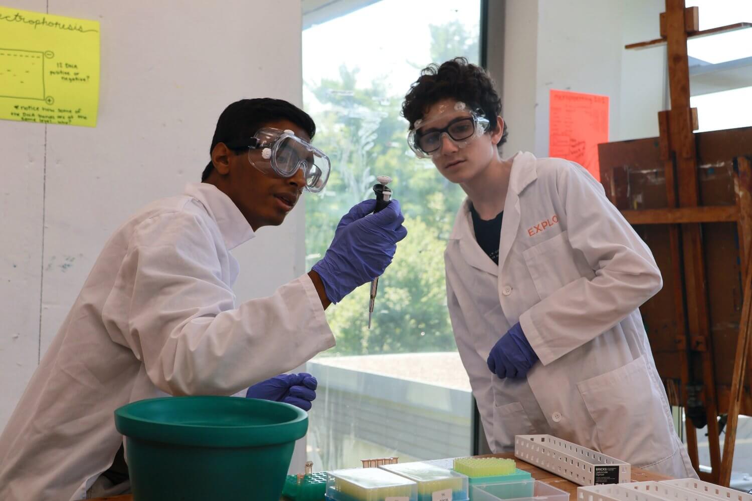 Two middle school students in lab coats engaging in a science experiment during a summer program at EXPLO.