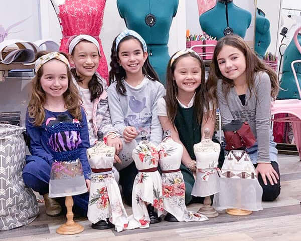 Kids at a fashion design summer camp in New York City showcase their creative clothing projects.