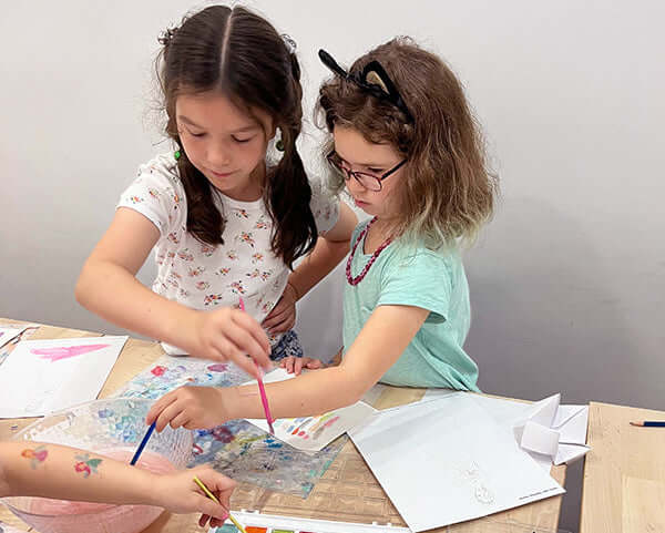 Kids engaged in creative fashion design activities at the Summer Camp in New York City, showcasing teamwork and artistic skills.