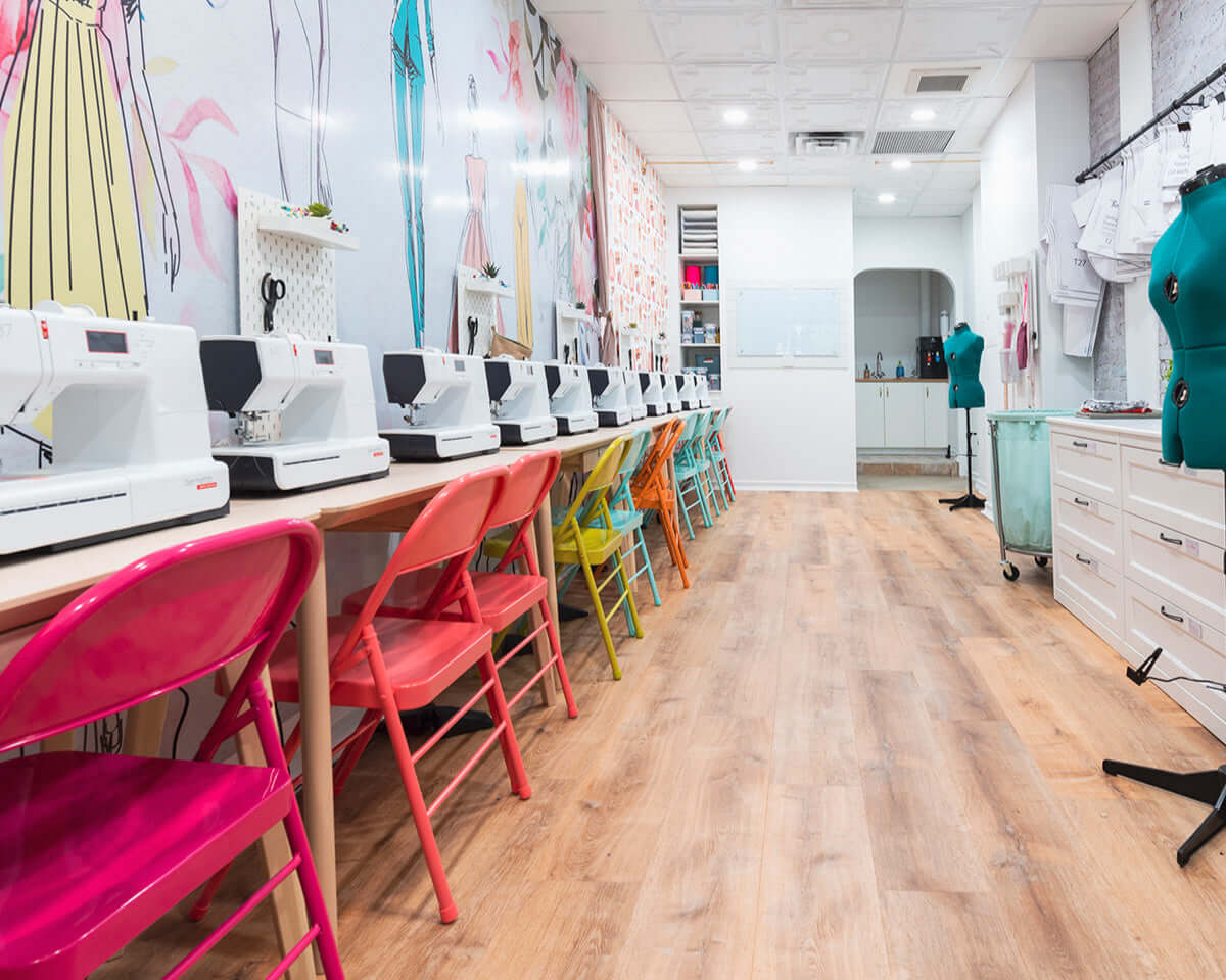 Colorful chairs and sewing machines in a vibrant NYC fashion design studio for kids' summer camp.